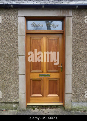 Une nouvelle porte en bois avec des raccords en laiton situé dans un vieux chalet de fer dans le village de Colliston, Arbroath en Ecosse. Banque D'Images