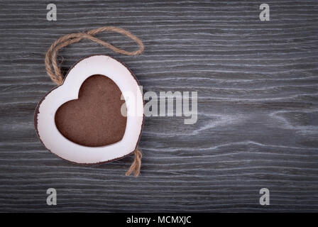 Dans le cadre photo en forme de coeur en bois gris sur fond de bois de chêne. Banque D'Images