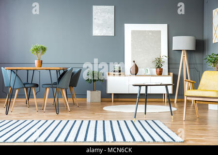 Tapis gris à rayures en appartement intérieur avec chaises table de salle à manger et les peintures sur le mur Banque D'Images