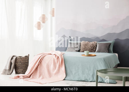 Panier à côté du lit avec couverture rose pastel à l'intérieur chambre à coucher avec vue sur la montagne de papier peint Banque D'Images