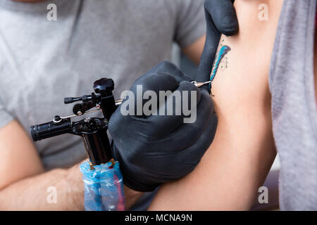 Mains d'un artiste prudent avec l'emballage en plastique à sec un nouveau tatouage coloré Banque D'Images