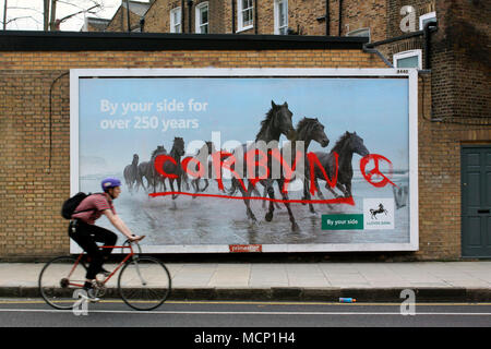 Londres, Royaume-Uni, 17 avril 2018, un cycliste à Islington, au nord de Londres, école passé une affiche pour la Banque Lloyds barbouillés de graffitis à l'appui de député local, Jeremy Corbyn Ersoy Emin Crédit : ersoy emin/Alamy Live News Banque D'Images