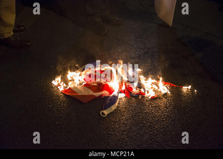 Athènes, Grèce. Apr 17, 2018. Les manifestants brûler le drapeau américain à l'extérieur de l'Ambassade américaine comme ils crier des slogans contre Trump, mai et Macron. Des milliers, des membres du parti communiste de Grèce ainsi que d'autres partis de gauche ont marché vers l'Ambassade Américaine pour protester contre la récente sur les grèves menées par les États-Unis sur la Syrie. Credit : Nikolas Georgiou/ZUMA/Alamy Fil Live News Banque D'Images