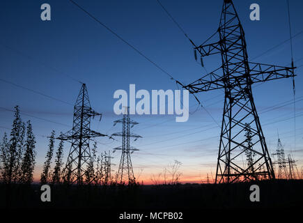 Pylônes à haute tension contre le coucher du soleil. Poteau électrique les lignes électriques et les fils. Banque D'Images