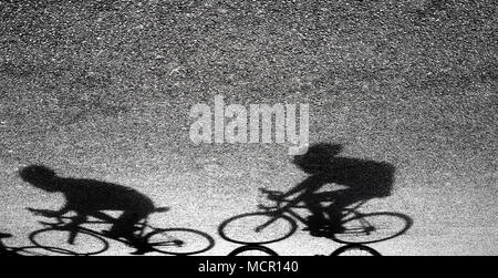 Silhouette floue et l'ombre de deux cyclistes professionnels en noir et blanc sur la route d'asphalte Banque D'Images