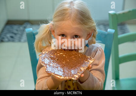 Portrait d'une jeune fille de 5 ans mange Matzo avec chocolat à tartiner pendant Pâque autorisation Modèle disponible Banque D'Images