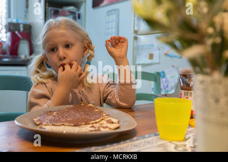 Portrait d'une jeune fille de 5 ans mange Matzo avec chocolat à tartiner pendant Pâque autorisation Modèle disponible Banque D'Images