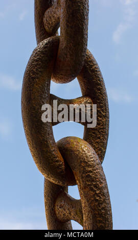 Une vieille chaîne rouillée sur fond bleu. Dans l'arrière-plan est bleu ciel avec des nuages blancs. Banque D'Images