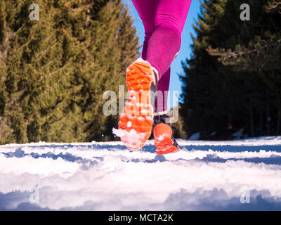 Girl with black Runner chaussures orange et lilas avec des leggings dans une forêt de pins enneigés Banque D'Images