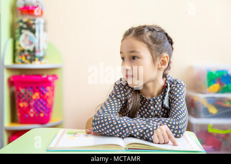 Cute little girl faire leurs devoirs, lire un livre, des pages à colorier, écrire et peindre. Les enfants de la peinture. Attirer les enfants. Bambin avec des livres à la maison. Les enfants d'âge préscolaire apprennent à lire et écrire. Tout-petits créatifs Banque D'Images