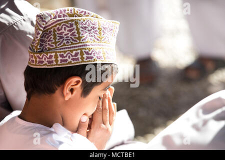 Nizwa, Oman - Mar 23, 2018 : Jeune garçon omanais en tenant son visage dans ses mains pendant un moment de calme. Banque D'Images