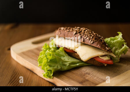 Sandwich de la lumière avec du fromage et de la tomate sur une surface en bois. Banque D'Images