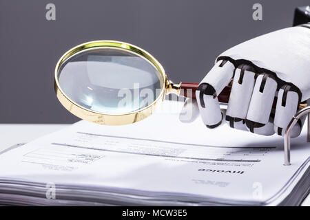 Close-up of a Robotic Hand Holding Loupe sur facture au lieu de travail Banque D'Images