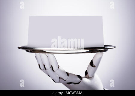 Main robotique Holding Blank Card dans la Plaque sur fond gris Banque D'Images