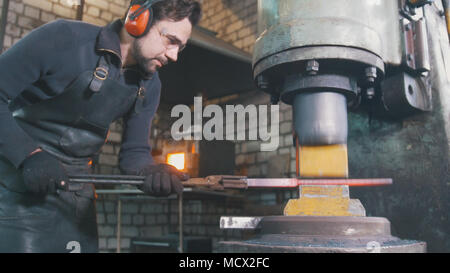 Blacksmith forge fer chaud rouge sur enclume - martelage automatique Banque D'Images