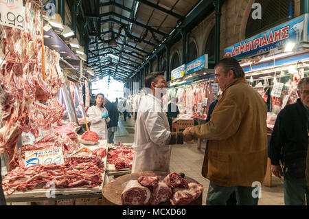 Athènes, Grèce - 29 Avril 2018 : un commerçant accueille un client à son étal de viande dans le célèbre marché grec à Athènes. Banque D'Images