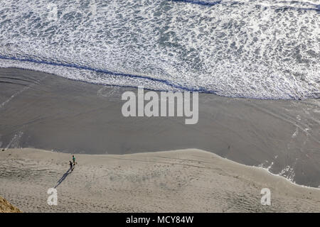 Une vue aérienne d'une personne qui marche le long de la plage avec des vagues en roulant. Banque D'Images