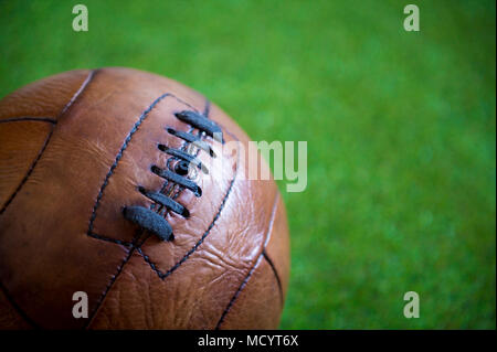 Vue rapprochée d'un vintage en cuir marron au football sur fond d'herbe verte luxuriante Banque D'Images