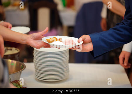 Serveur sert de viande rôtie et pommes de terre au four à la fête ou réception de mariage Banque D'Images