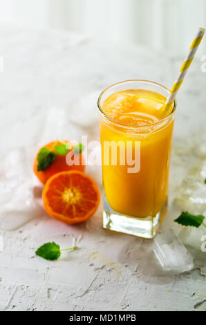 Le jus d'orange avec de la glace et de tangerines sur fond blanc. Espace libre pour votre texte. Copyspace. Boissons froides pour chaude journée d'été. Banque D'Images