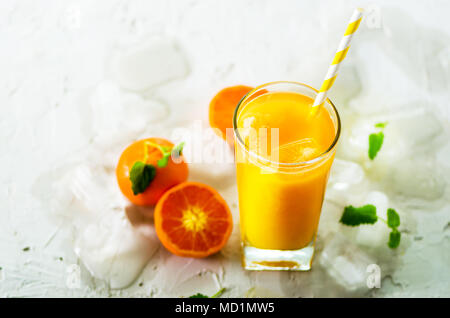 Le jus d'orange avec de la glace et de tangerines sur fond blanc. Espace libre pour votre texte. Copyspace. Boissons froides pour chaude journée d'été. Banque D'Images