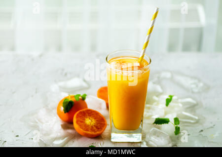 Le jus d'orange avec de la glace et de tangerines sur fond blanc. Espace libre pour votre texte. Copyspace. Boissons froides pour chaude journée d'été. Banque D'Images