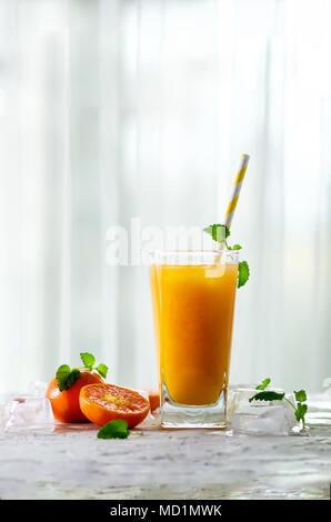 Le jus d'orange avec de la glace et de tangerines sur fond blanc. Espace libre pour votre texte. Copyspace. Boissons froides pour chaude journée d'été. Banque D'Images