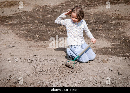 Fille de creuser dans le sol organique sèche par binette. Banque D'Images