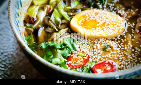 Soupe de Ramen dans un bol. Saveur riche bouillon de poulet avec la pâte de miso, grillé du poulet teriyaki, poireaux, champignons, oeufs marinés, nouilles aux oeufs, l'oignon, le chili pe Banque D'Images