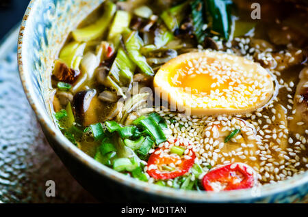 Soupe de Ramen dans un bol. Saveur riche bouillon de poulet avec la pâte de miso, grillé du poulet teriyaki, poireaux, champignons, oeufs marinés, nouilles aux oeufs, l'oignon, le chili pe Banque D'Images