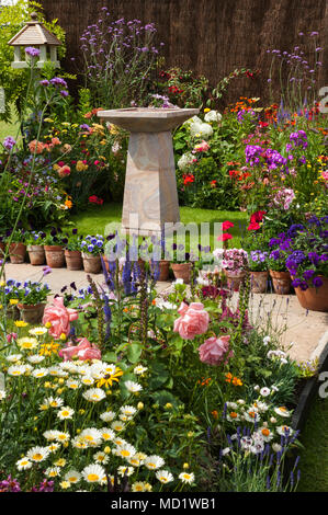 Plantes à fleurs d'été de couleurs vives sur les frontières, chemin & stone birdbath - French Chalet jardin afficher, RHS Flower Show, Tatton Park, Angleterre, RU Banque D'Images