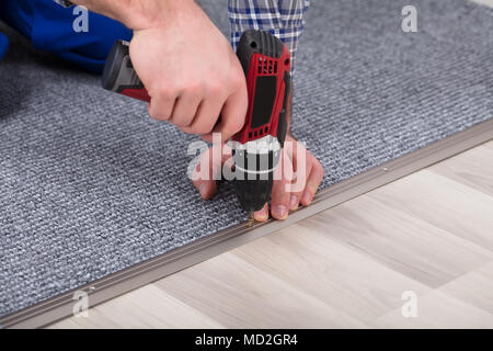 Close-up d'un ajusteur de Tapis Tapis gris la main de l'installation avec tournevis sans fil Banque D'Images