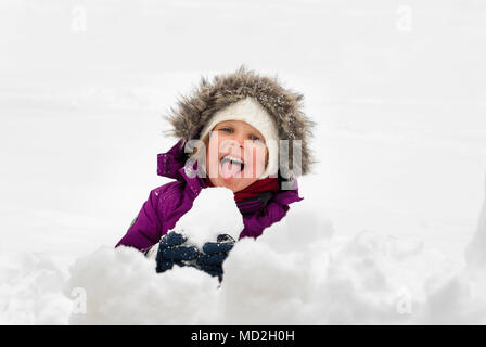 Une petite fille sticking out tongue en mangeant de la neige. Banque D'Images