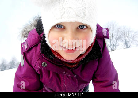 Baby Girl dans la neige sur un fond d'hiver. Banque D'Images