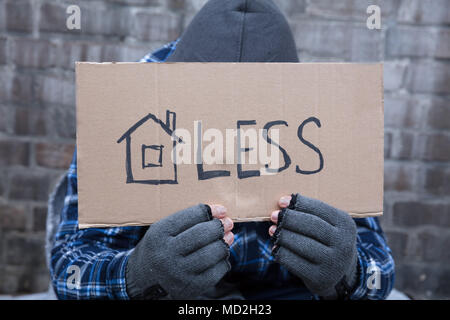 Beggar's Hand Holding avec des gants sans-abri placard en face de son visage Banque D'Images