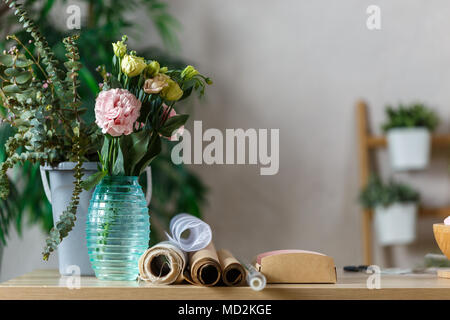 Photo d'un fleuriste avec vase de fleurs sur table à fond de plantes d'intérieur Banque D'Images