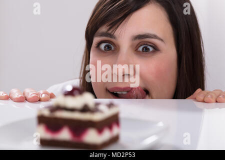Jeune femme envie de manger tranche de gâteau de lécher ses lèvres Banque D'Images