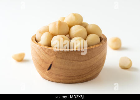 Les noix de macadamia dans bol en bois sur fond blanc Banque D'Images