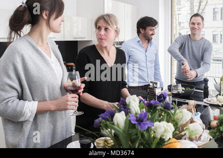 Groupe d'amis de désinvolture snacking sur une sélection de produits alimentaires tout en rire et s'amuser. Banque D'Images