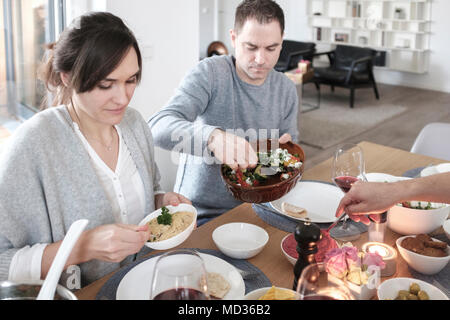 Groupe d'amis de désinvolture snacking sur une sélection de produits alimentaires tout en rire et s'amuser. Servir des légumes grillés- selective focus Banque D'Images