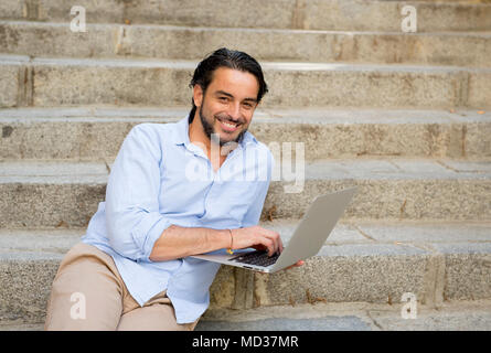 Young attractive l'homme assis sur un escalier de la ville travaillant avec un ordinateur portable à la satisfait et confiant dans les nouvelles technologies d'affaires et les natures mortes Banque D'Images