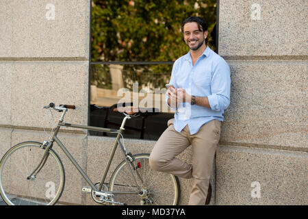 Young happy man attrayant dans les vêtements à la mode casual smiling cheerful using mobile phone on vintage rétro cool location dans les natures mortes moderne et élégant Banque D'Images