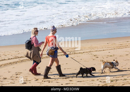 Bournemouth, Dorset, UK. 18 avril 2018. Météo France : belle chaude journée ensoleillée à plages de Bournemouth avec un ciel bleu et soleil ininterrompue, en tant que visiteurs, chef de la mer pour profiter de la journée la plus chaude de l'année jusqu'à présent. Deux jeunes chiens femme marche le long du littoral. Mini vague. Credit : Carolyn Jenkins/Alamy Live News Crédit : Carolyn Jenkins/Alamy Live News Banque D'Images