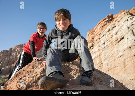 Portrait de garçons assis sur le roc, sticking out tongue, Lone Pine, Californie, USA Banque D'Images