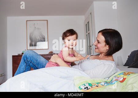 Mère et fille de bébé détente sur lit Banque D'Images