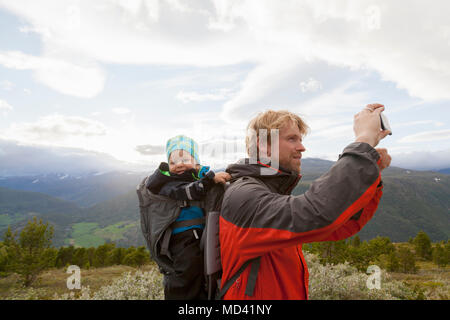 Male hiker avec fils photographie paysage de montagne, le parc national de Jotunheimen, Lom, Oppland, Norvège Banque D'Images