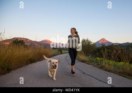 Jeune femme tournant le long chemin rural avec chien Banque D'Images