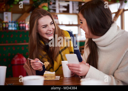 Les jeunes femmes smiling over text message on mobile phone Banque D'Images