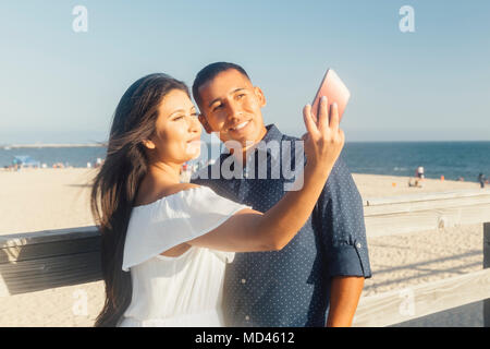 Couple près de la plage, à parler, à l'aide de selfies smartphone, Seal Beach, California, USA Banque D'Images