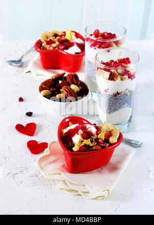 Petit-déjeuner romantique avec chia, granola, yogourt et fruits rouges sur fond de béton blanc. Santé et alimentation concept Banque D'Images